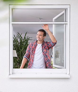 Mann an einem offenen Fenster mit Fliegengitter von Systec 