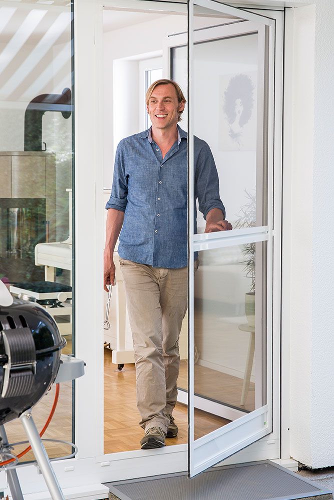 Mann der gerade eine Pendeltür als Insektenschutztür öffnet